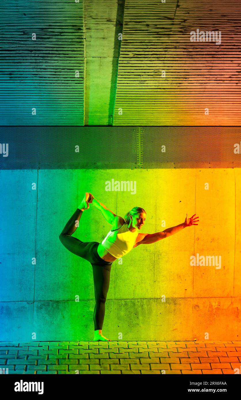 Frau, die vor einer neonfarbenen Wand Yoga macht Stockfoto