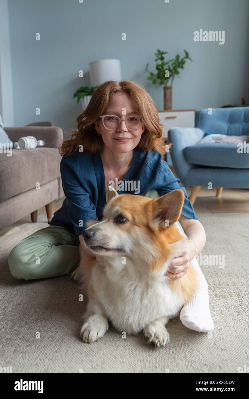 Frau mit walisischem Corgi-Hund sitzt im Wohnzimmer Stockfoto