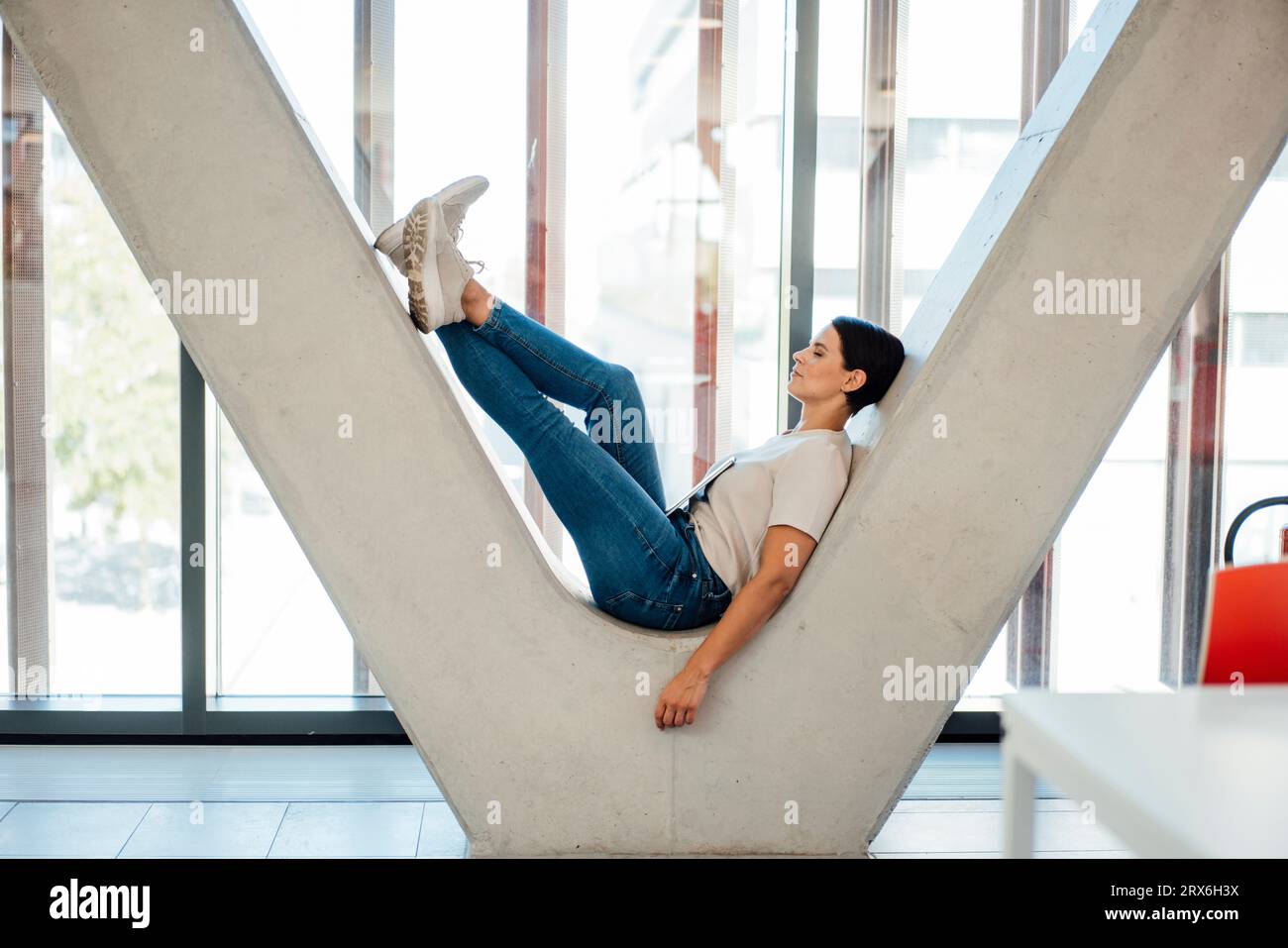 Geschäftsfrau auf V-förmiger Säule im Büroflur Stockfoto