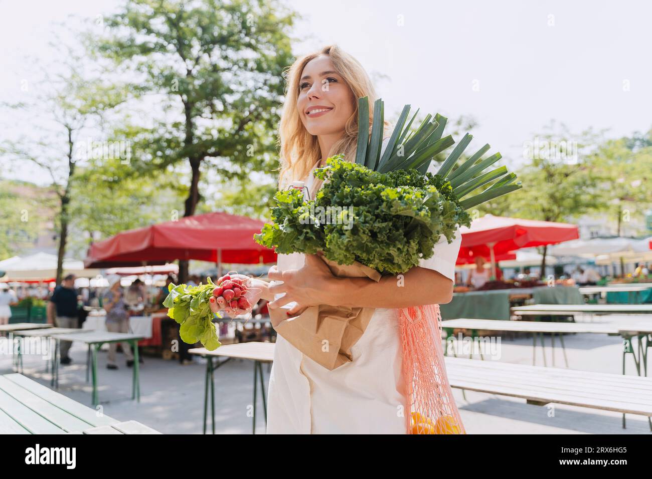 Glückliche Frau, die frisches Blattgemüse auf dem Bauernmarkt hält Stockfoto