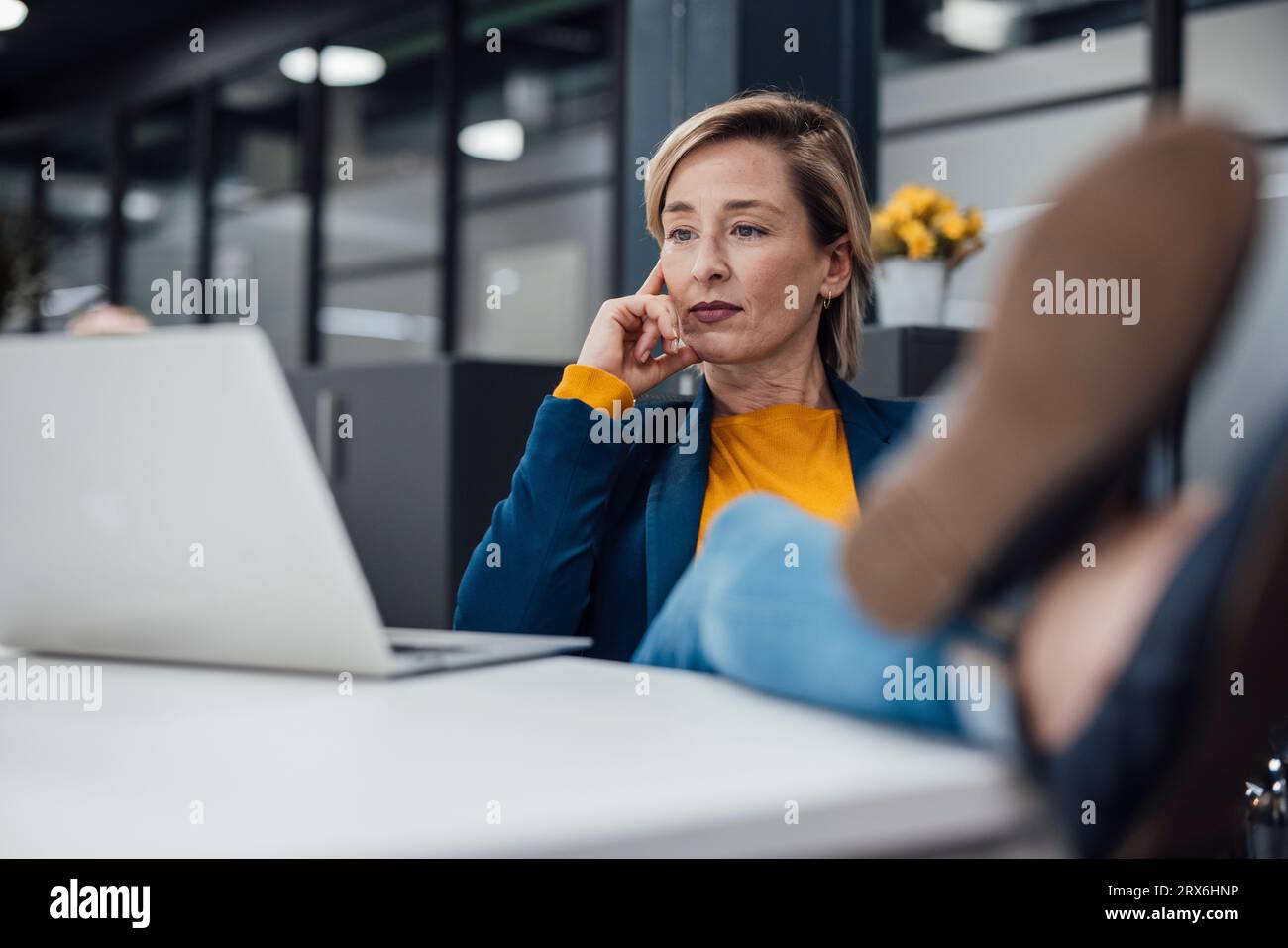 Eine durchdachte Geschäftsfrau, die am Schreibtisch im Büro ein Brainstorming über einem Laptop machte Stockfoto