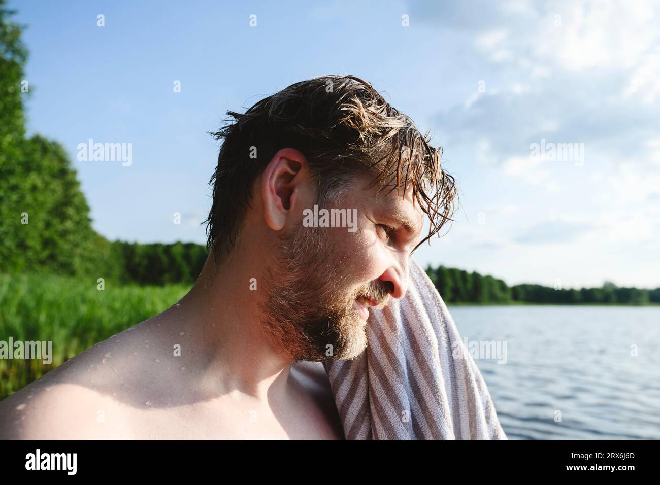 Mann wischt Haare mit Handtuch in der Nähe des Sees ab Stockfoto