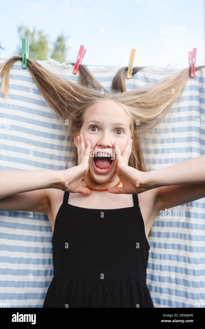 Überraschtes blondes Mädchen mit Haaren in Clothespin Stockfoto