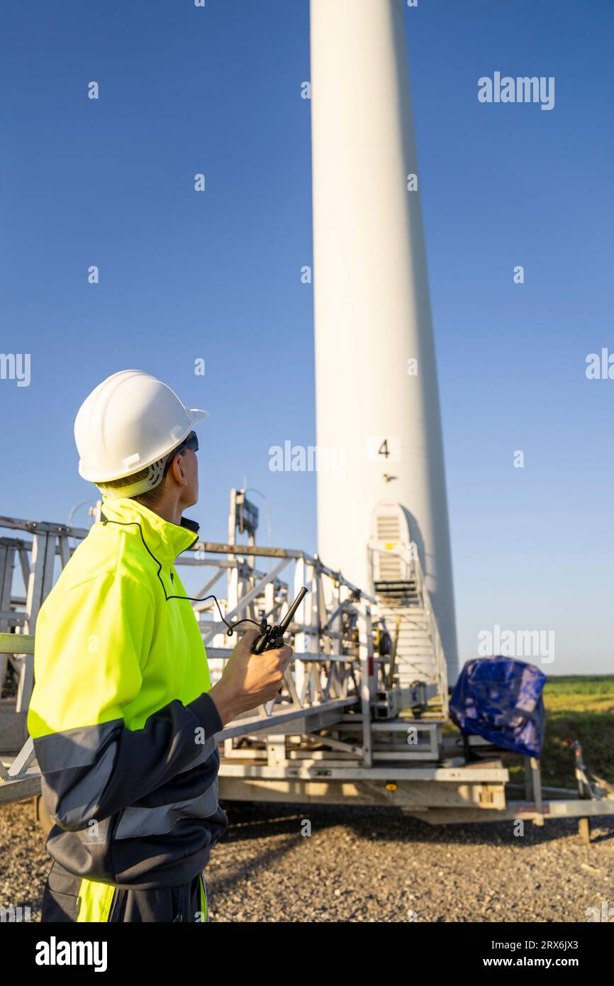 Ingenieur, der an sonnigen Tagen die Wartungsmaschine für Windkraftanlagen betrachtet Stockfoto