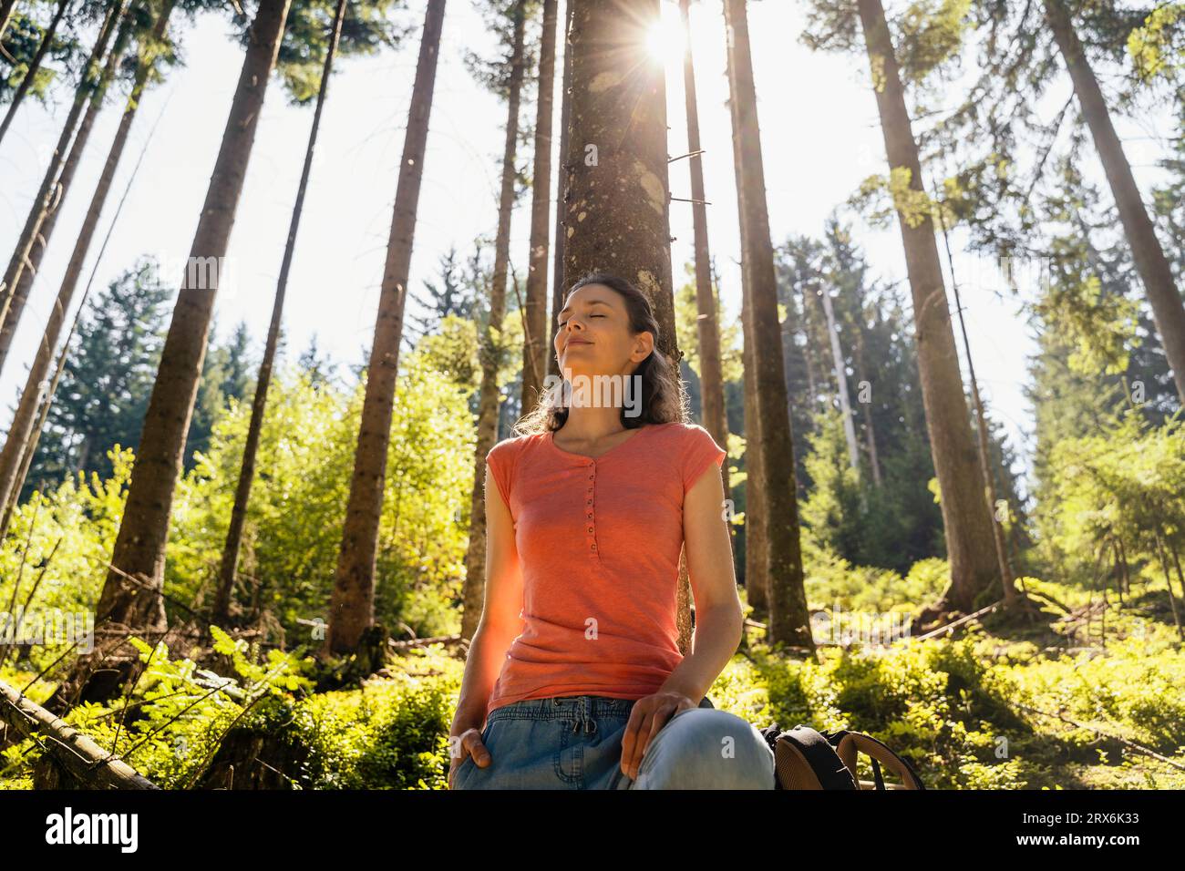Frau mit geschlossenen Augen im Wald an sonnigen Tagen Stockfoto