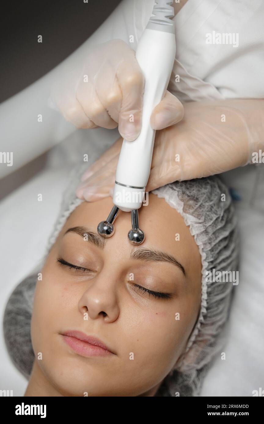 Hände des Dermatologen mit Geräten auf der Stirn der Frau massieren Stockfoto