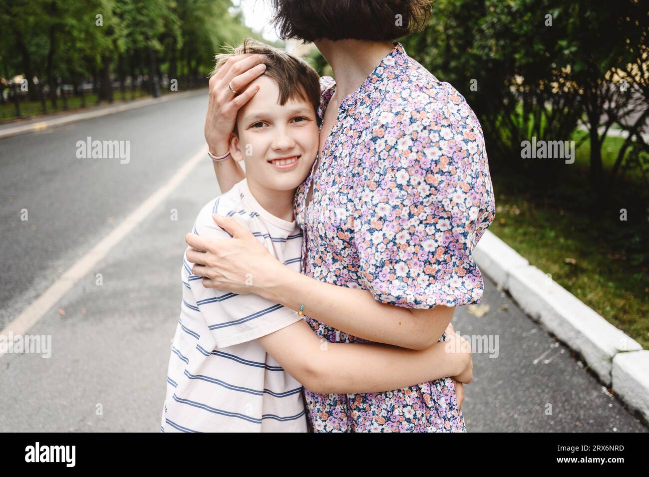 Glücklicher Junge umarmt Mutter auf der Straße Stockfoto