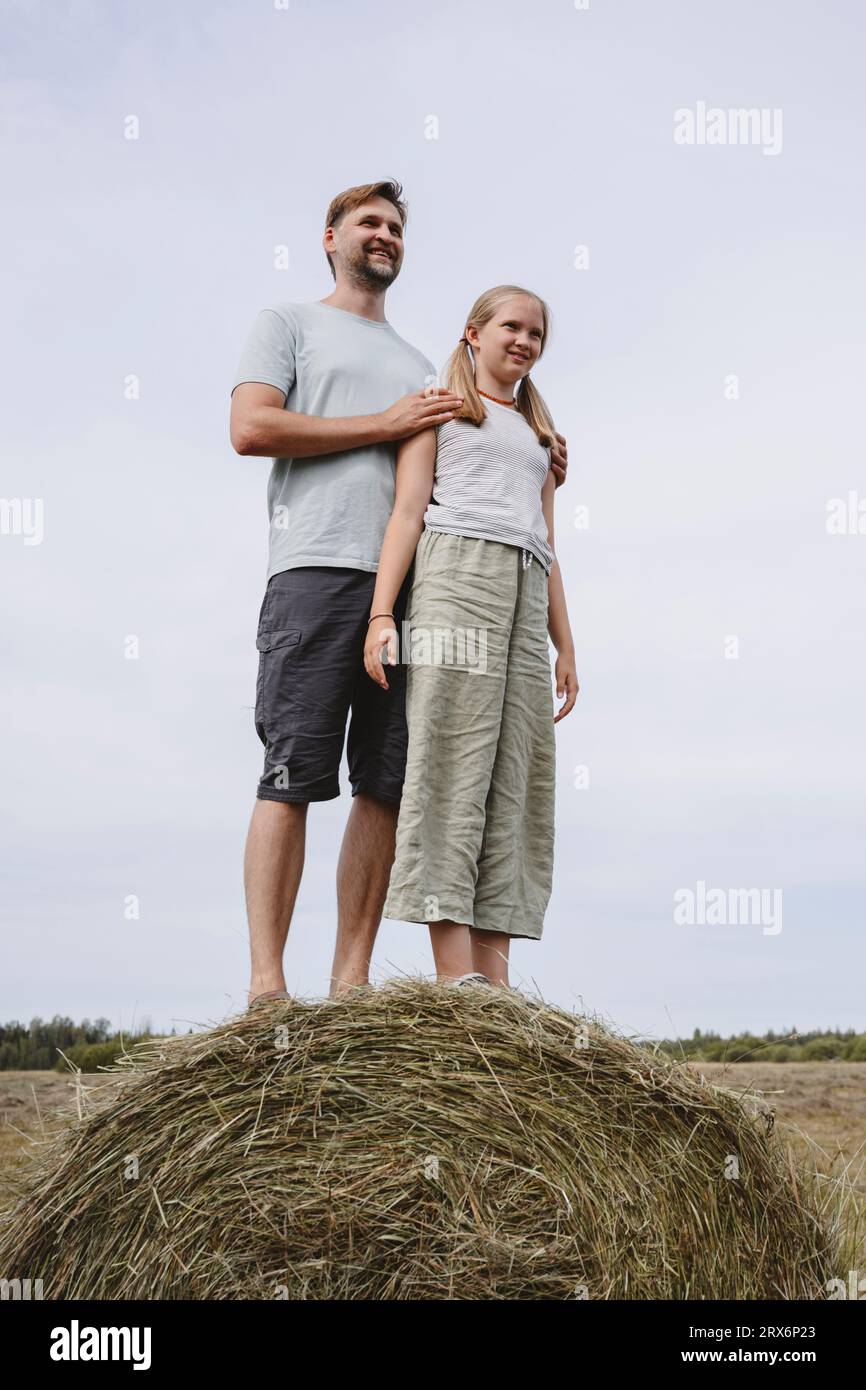 Glücklicher Vater und Tochter, die auf dem Feld auf Heu stehen Stockfoto