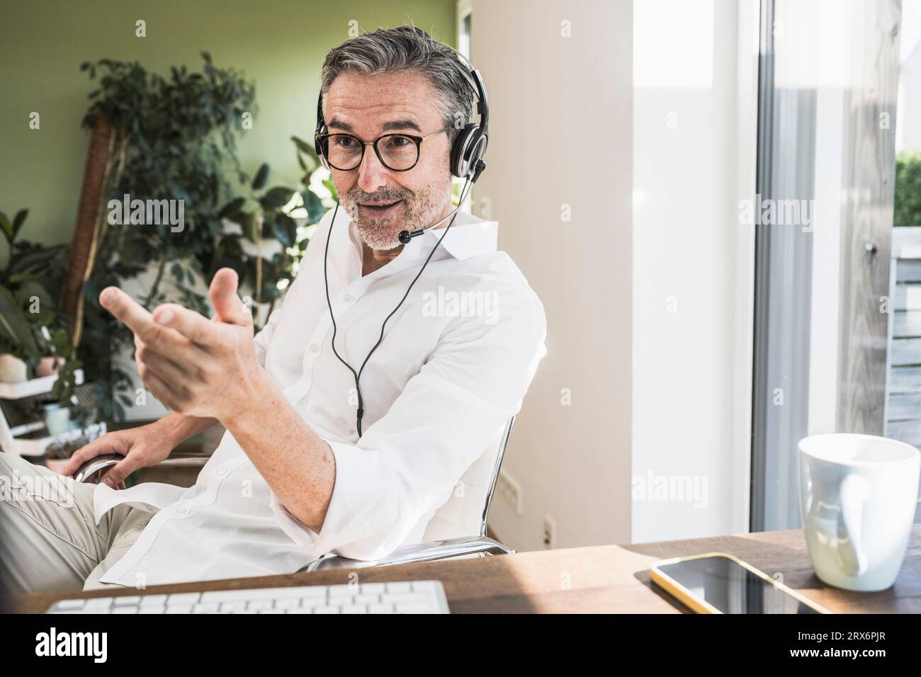 Vertriebsmitarbeiter, der im Home Office über das Headset spricht Stockfoto Vertriebsmitarbeiter, der im Home Office über das Headset spricht Stockfoto