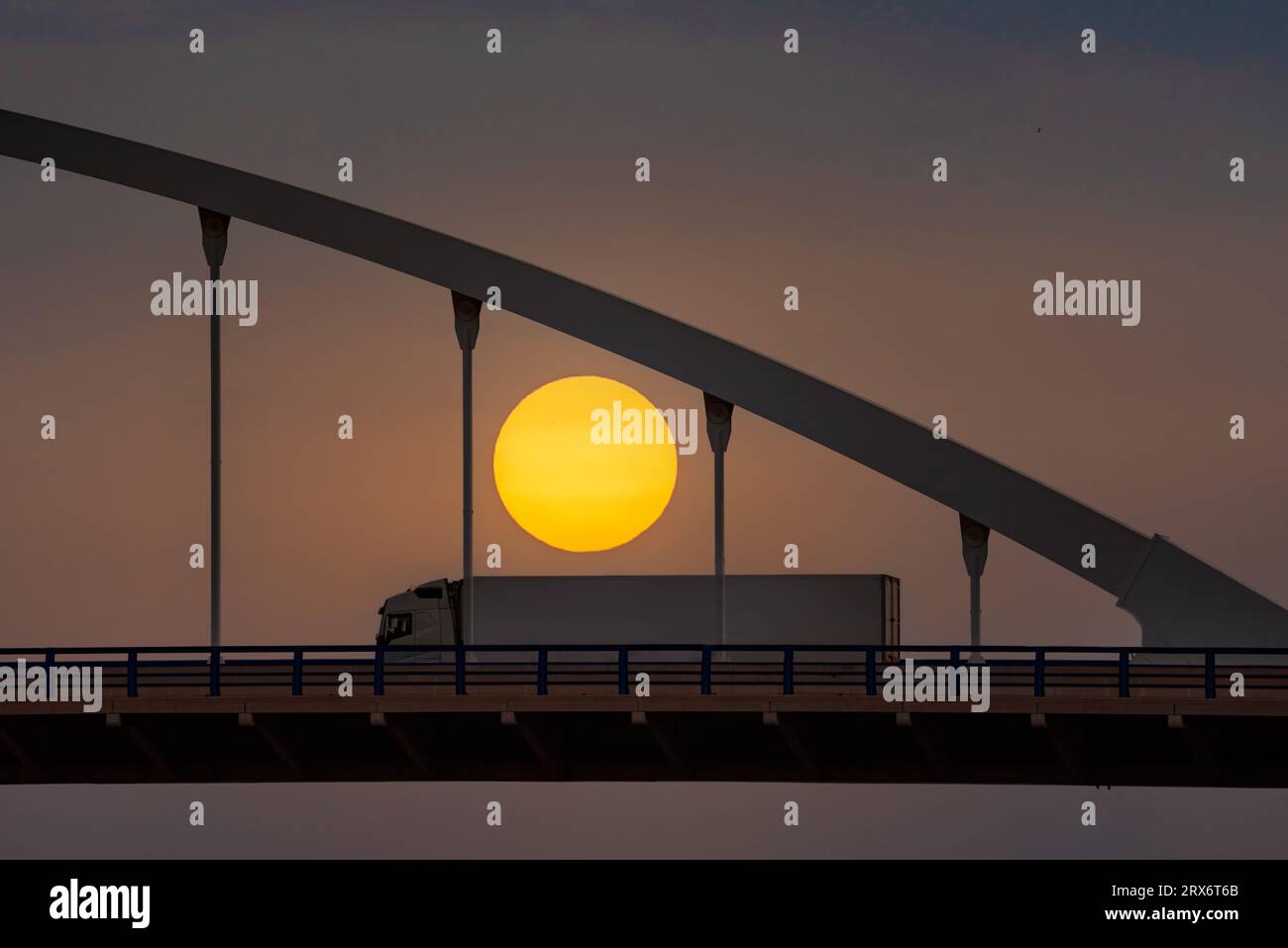 Kühlwagen fährt auf einer Brücke mit der Sonne im Hintergrund. Stockfoto