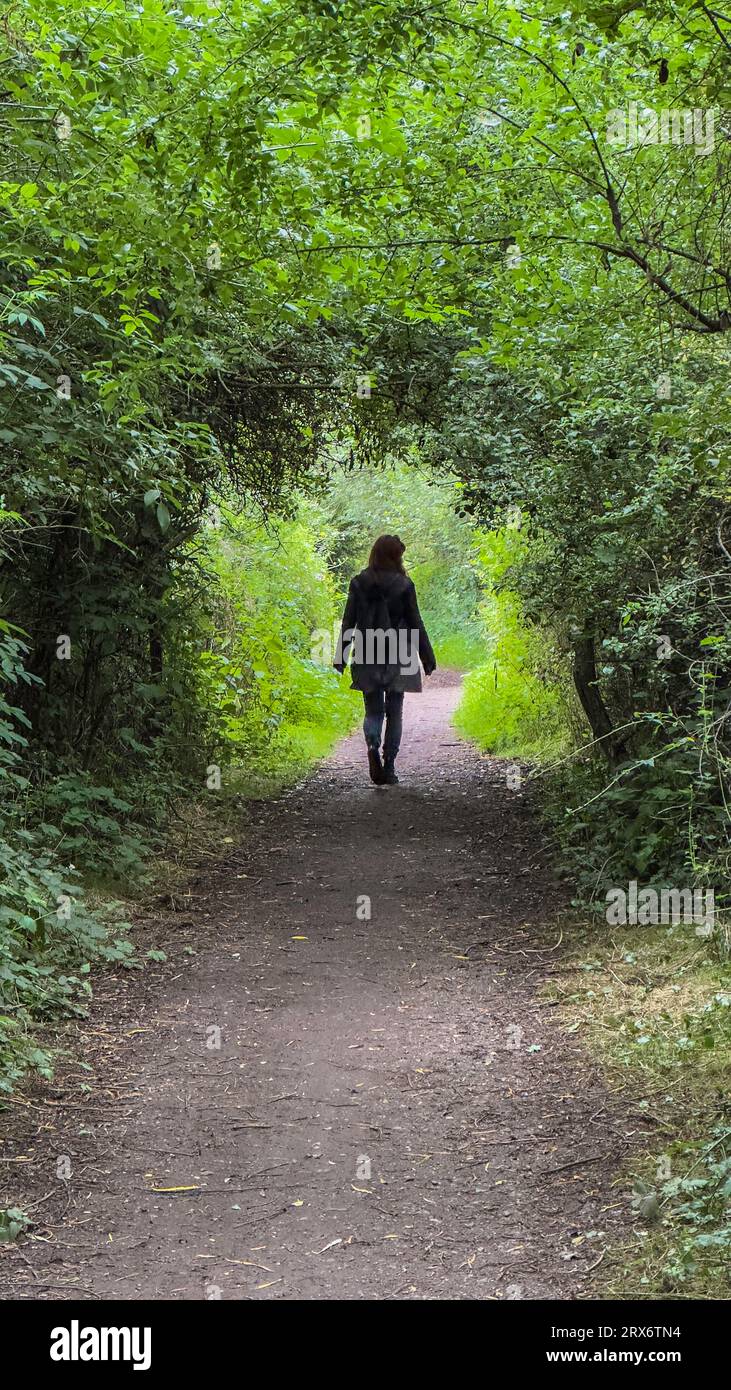 Mädchen, das vor der Kamera durch einen Baumbogen in Trentside, Gunthorpe, Nottingham, England, Großbritannien, läuft Stockfoto