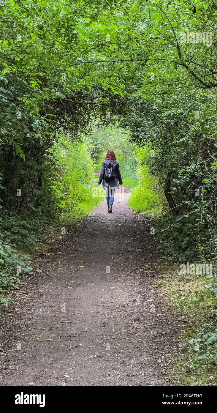 Mädchen, das vor der Kamera durch einen Baumbogen in Trentside, Gunthorpe, Nottingham, England, Großbritannien, läuft Stockfoto