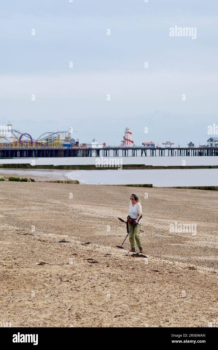 Frau, die Metall am Strand von Clacton auf See entdeckt. Stockfoto