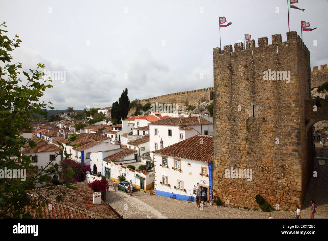 Mauern und Türme mit Zinnen umgeben die blumengeschmückten Häuser von Obidos in der Provinz Estremadura, Portugal Stockfoto
