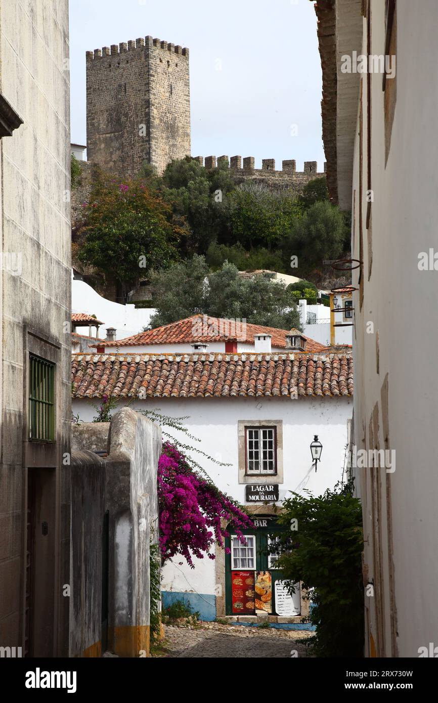 Mauern und Türme mit Zinnen umgeben die blumengeschmückten Häuser von Obidos in der Provinz Estremadura, Portugal Stockfoto