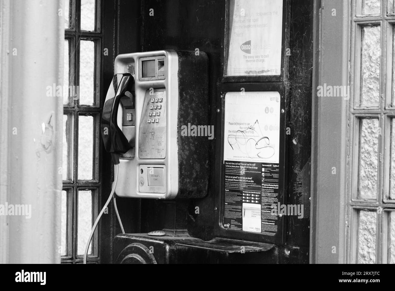 Alte rote Telefonbox, öffentliche Telefonkioske werden in der modernen Zeit selten mit Mobiltechnologie benutzt und werden daher nicht gut gepflegt. Nahaufnahme des Fotos Stockfoto