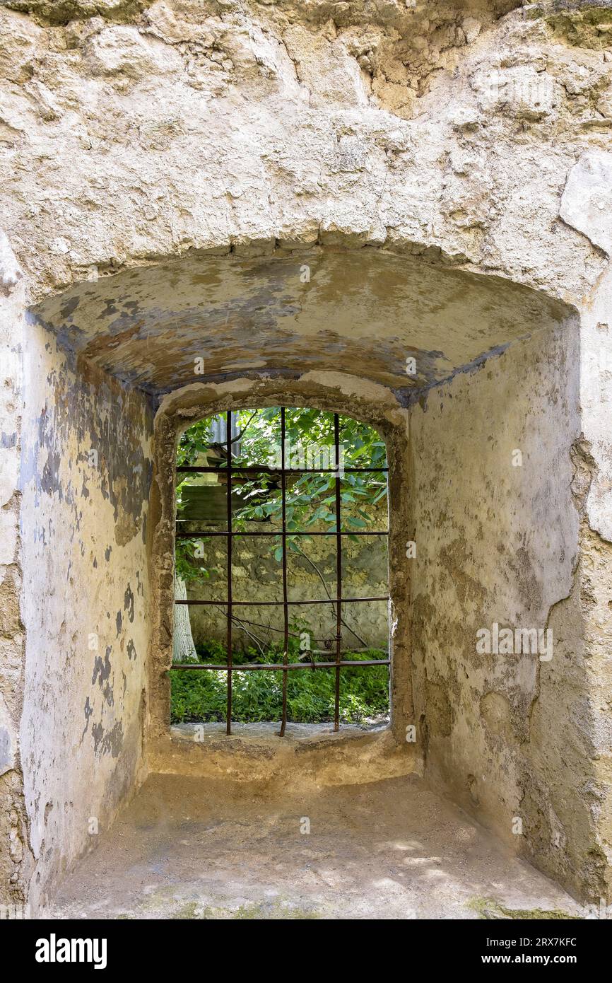 Fenster mit Gitter in Mauerwerk eines alten Gebäudes. Ein Bogenfenster mit Metallstangen an der Wand eines alten Hauses. Leerzeichen kopieren. Selektiver Fokus. Stockfoto Fenster mit Gitter in Mauerwerk eines alten Gebäudes. Ein Bogenfenster mit Metallstangen an der Wand eines alten Hauses. Leerzeichen kopieren. Selektiver Fokus. Stockfoto