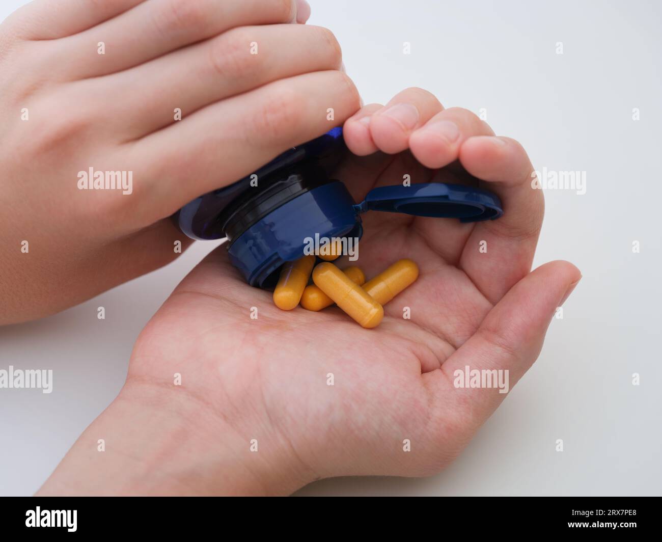 Eine Person, die Vitamin B-Komplex in die Handfläche gießt, wird aus einer Flasche in die Handfläche geschüttet. Nahaufnahme. Stockfoto