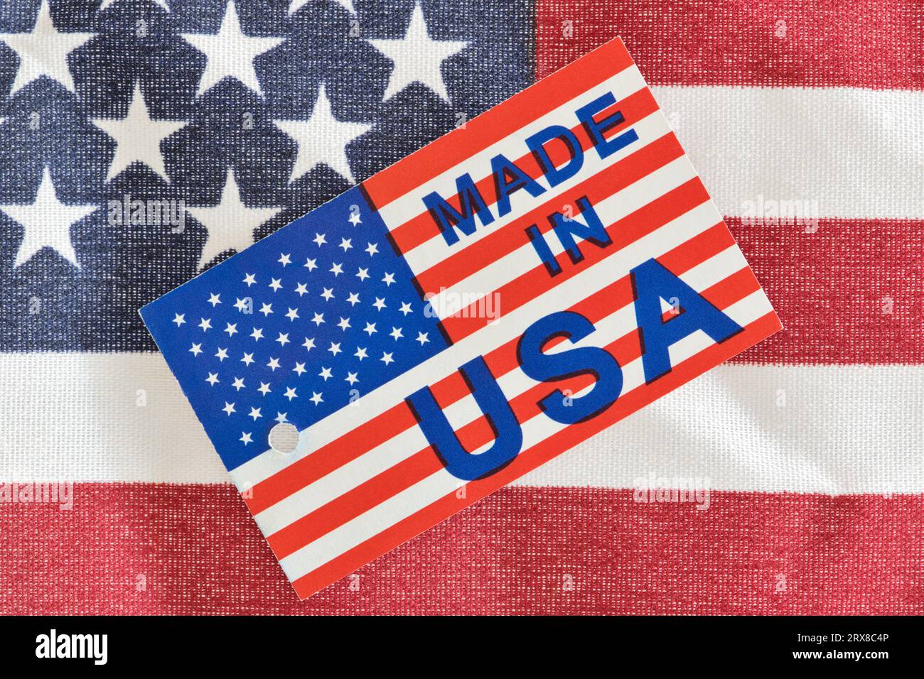 Made in USA-Produktetikett, das als Economy-Konzept auf einer teilweise amerikanischen Flagge sitzt. Makrobild mit patriotischen Hintergrunddetails. Stockfoto