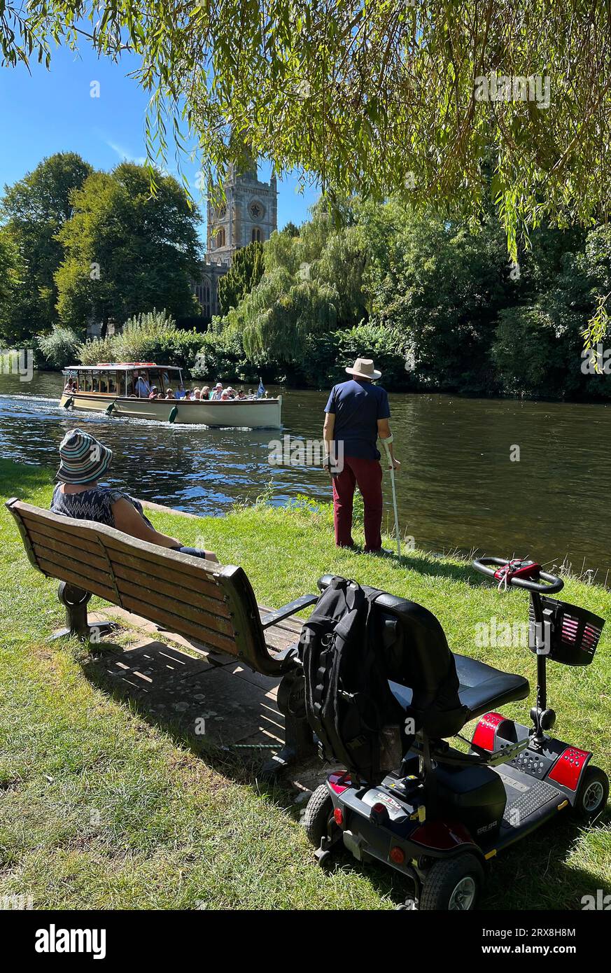 Ein Mann steht am Ufer des Flusses Avon und beobachtet an einem Sommertag in Stratford upon Avon ein vorbeifahrendes Boot. September 2023. Stockfoto