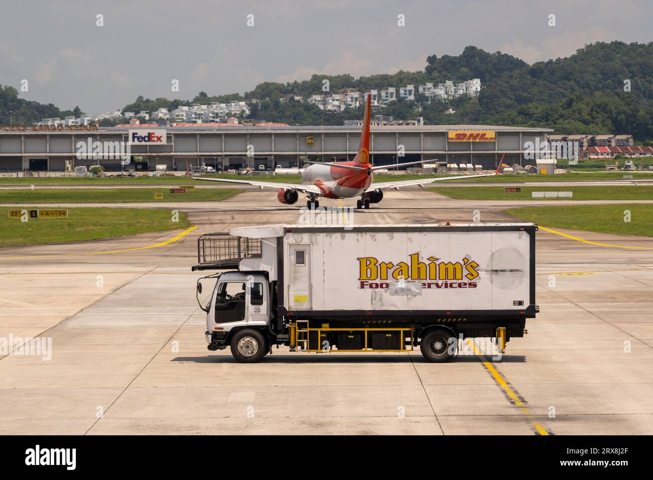 Ein Brahims Airport Food Truck auf dem Vorplatz mit einem abfliegenden Flugzeug im Hintergrund am Penang International Airport, Pulau Pinang, Malaysia Stockfoto