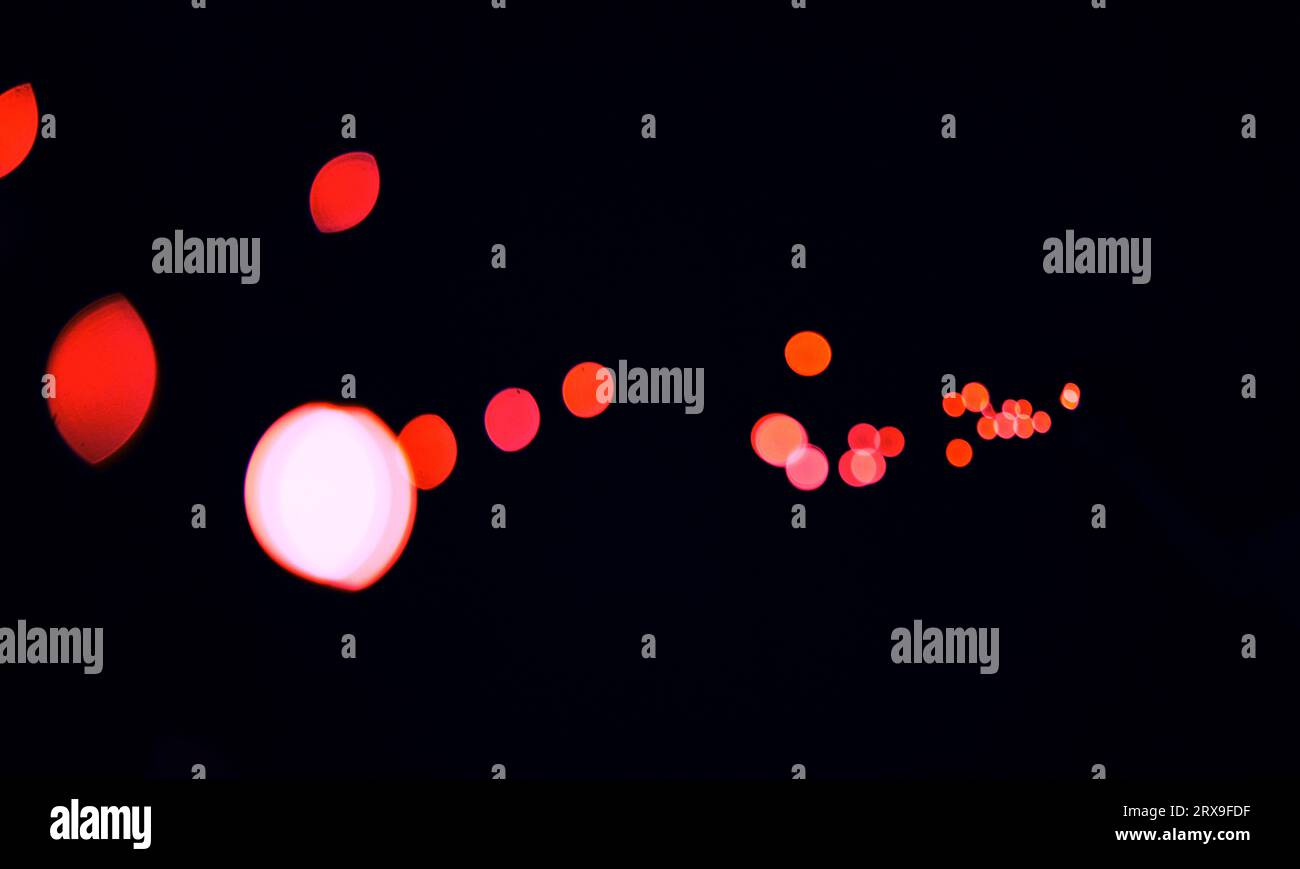 Bokeh, kosmische rote Punkte und schwarzer Hintergrund mit Muster, Textur und Mockup mit ästhetischen Lichtern. Nachtbeleuchtung, glitzernde Partikel und Leuchten im Dunkeln Stockfoto