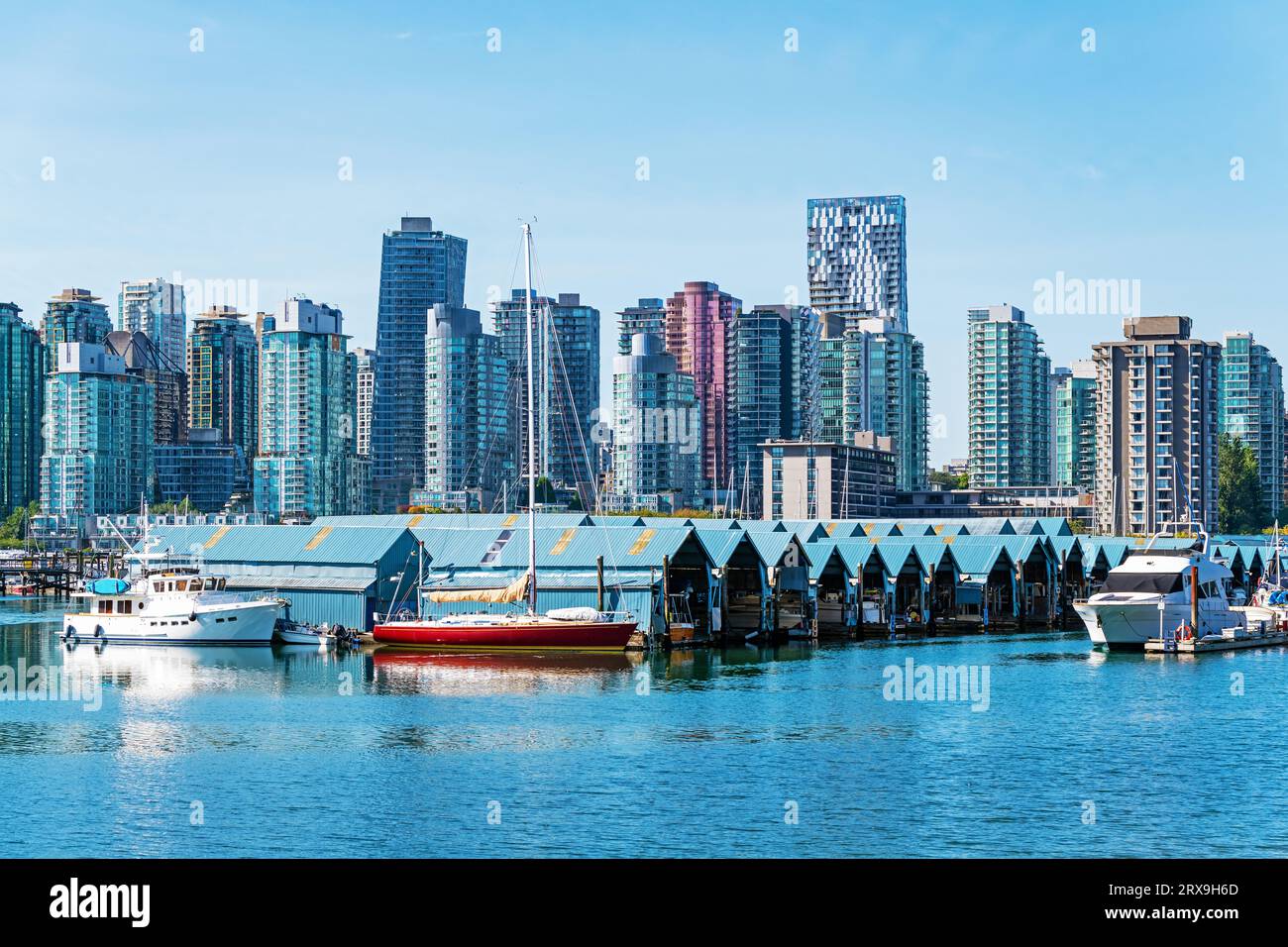 Yachtclub mit überdachter Konstruktion für Schiffe, die vom Seawall des Stanley Park mit der Skyline der Innenstadt von Vancouver, Kanada, aus gesehen werden. Stockfoto