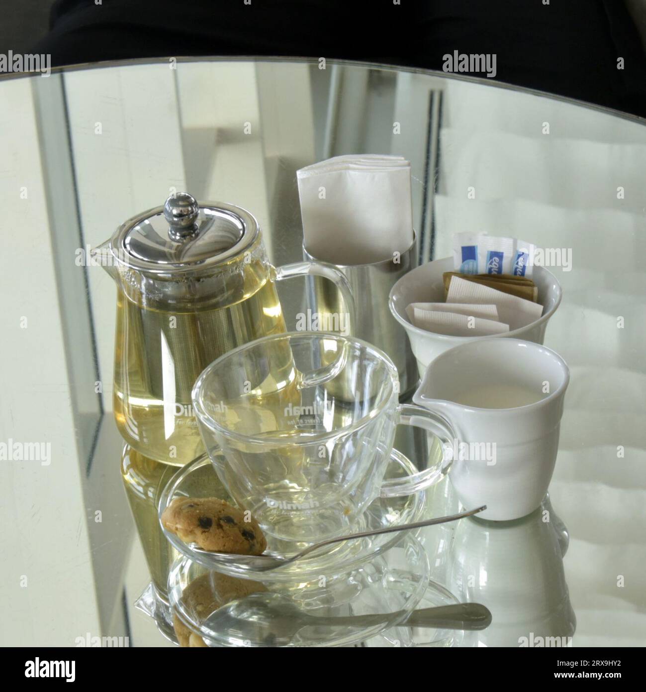 Teekanne und Tasse aus klarem Glas spiegeln sich in einem Spiegel Stockfoto