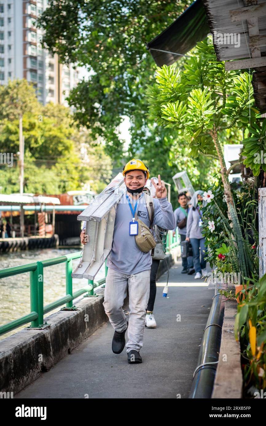 Einige sehr fröhliche Bauarbeiter lächeln für meine Kamera, während sie entlang des Saen Saep Canal Path in Bangkok, Thailand laufen. Stockfoto