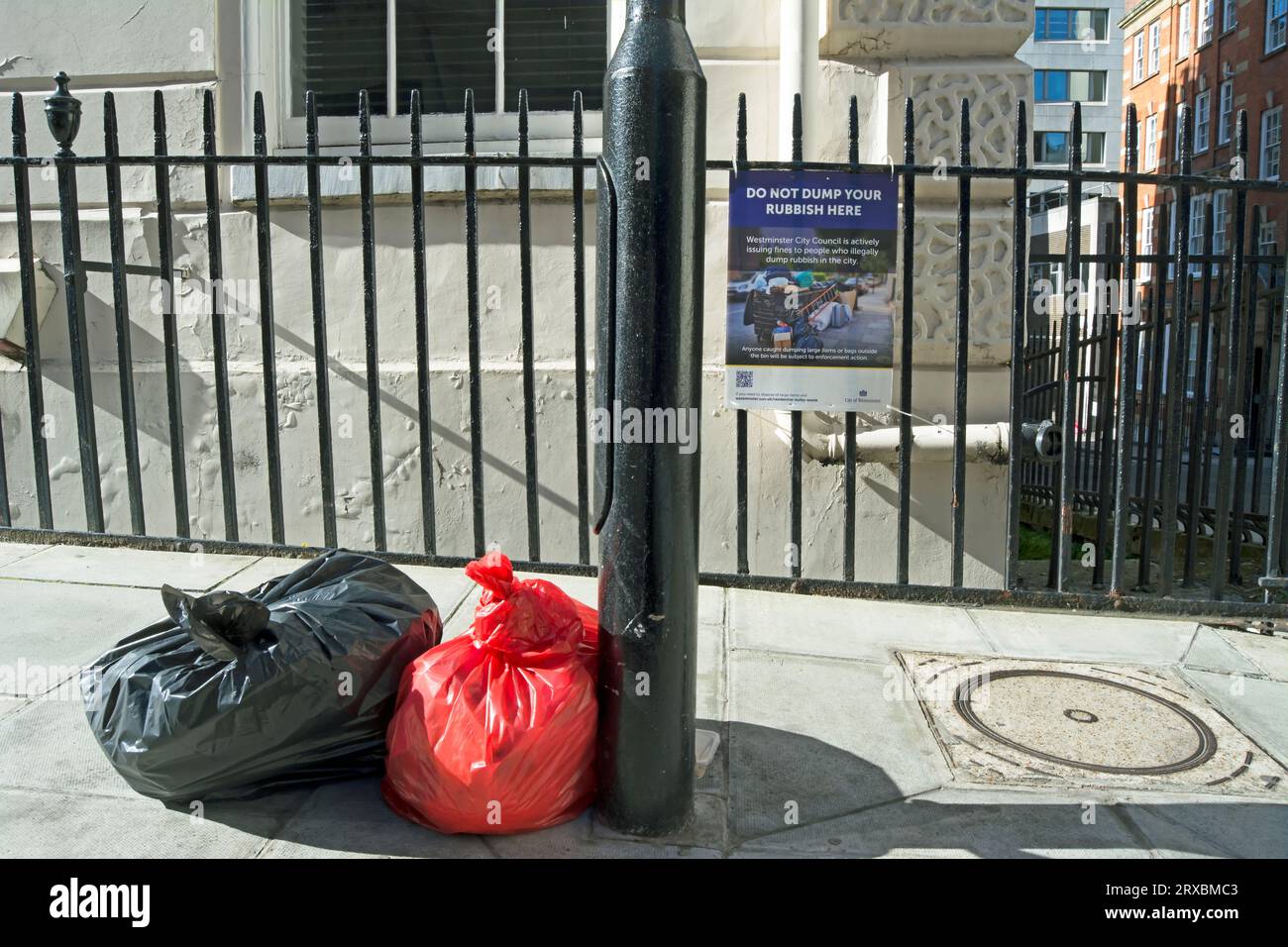Hinter zwei Tüten Müll auf der Straße, eine Bekanntmachung des westminster council, die besagt, dass Sie Ihren Müll hier nicht abladen sollten, robert Street, london, england Stockfoto