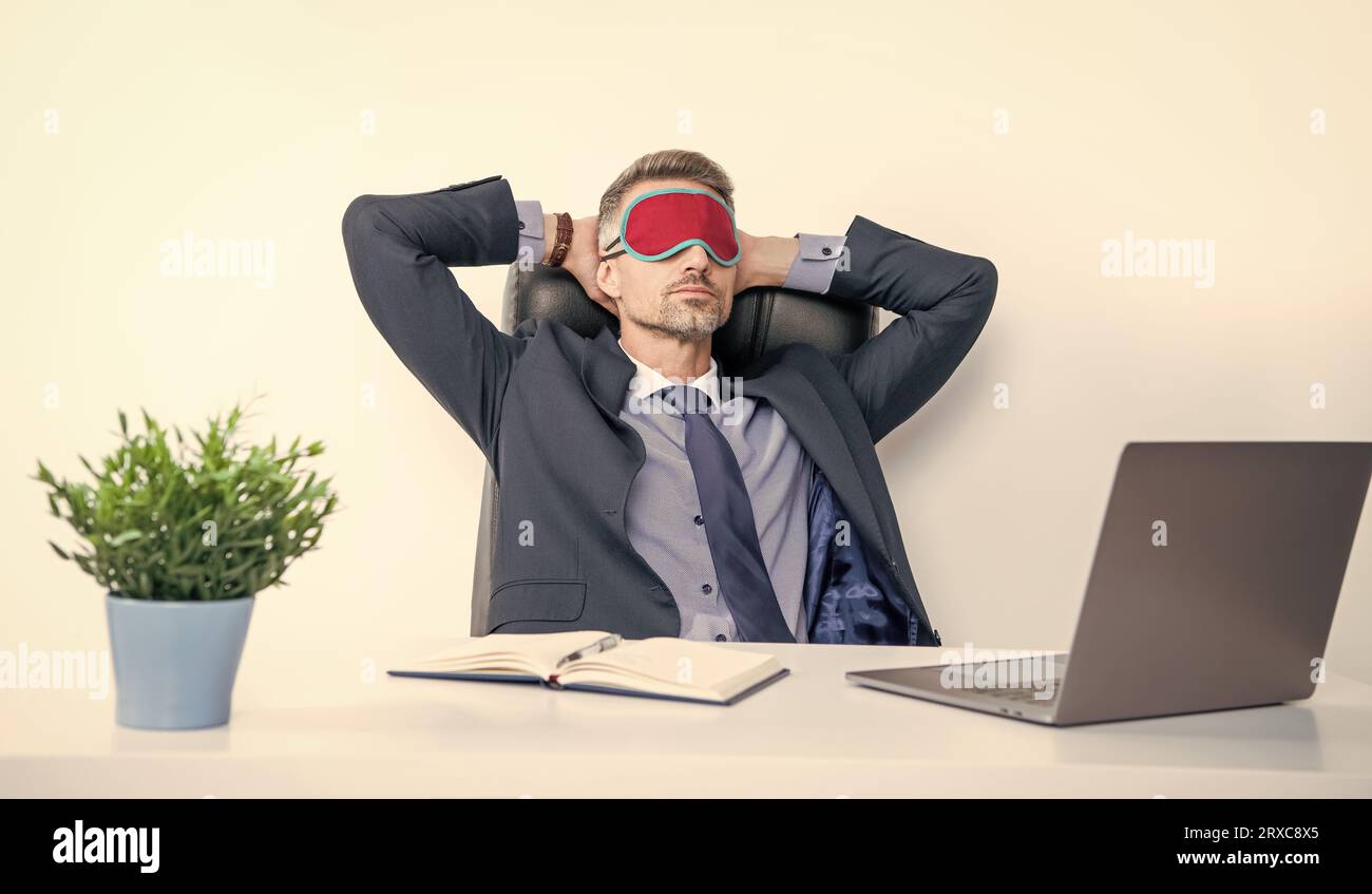 Müde Unternehmer entspannen in Schlafmaske am Arbeitsplatz. Stockfoto