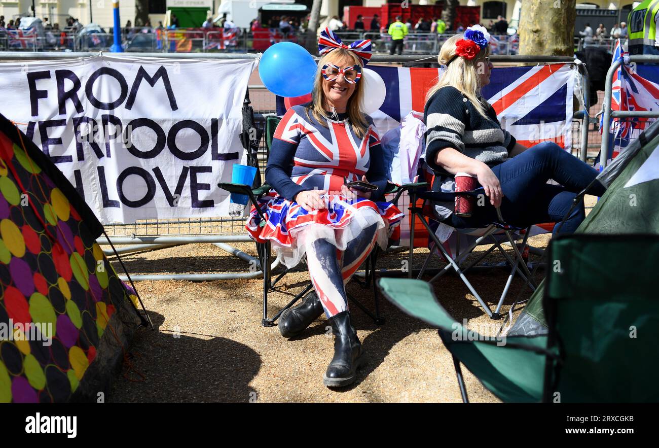 Eine Dame in Unions-Jack-Kleidung lächelt mit Freunden, die sich einen Tag vor der Krönung von König Charles ihren Platz in der Mall gesichert haben Stockfoto