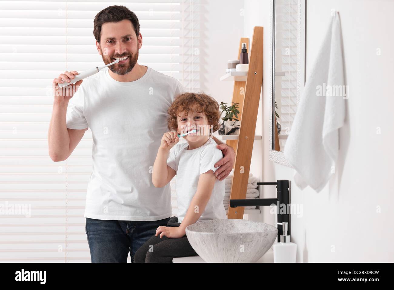 Vater und sein Sohn putzen sich im Bad die Zähne Stockfoto