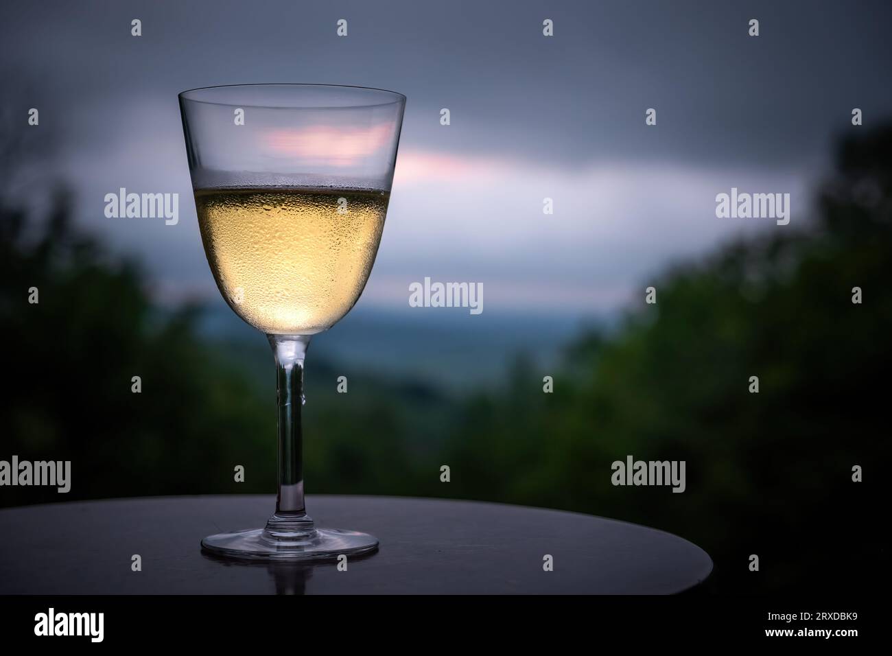 Ein kühles Glas Weißwein erwartet Sie, wenn die Sonne über einer natürlichen Landschaft untergeht. Stockfoto