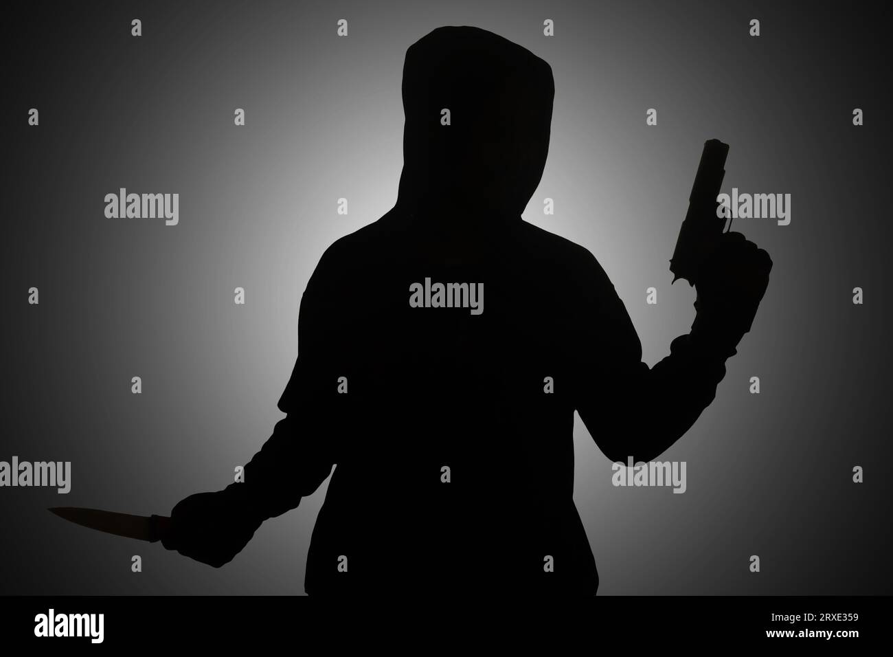 Mysteriöser Mann mit schwarzem Hoodie, der eine Pistole hält und mit einer Waffe schießt, während er ein Messer hält. Silhouette und dunkles Konzeptbild Stockfoto