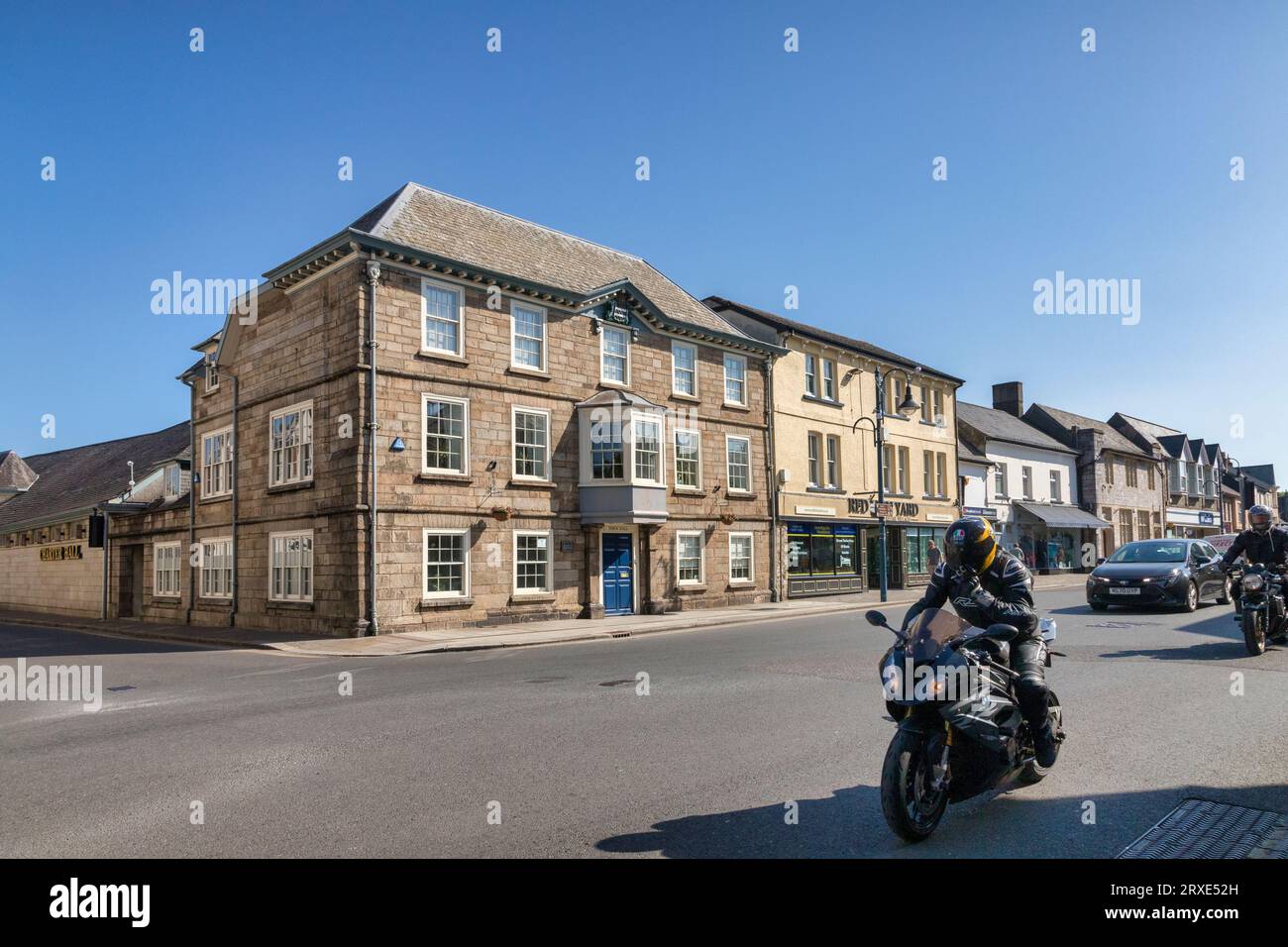3. Juni 2023: Okehampton, Devon, UK - Rathaus und historische Gebäude in der Okehampton High Street, auch Radfahrer fahren durch. Stockfoto