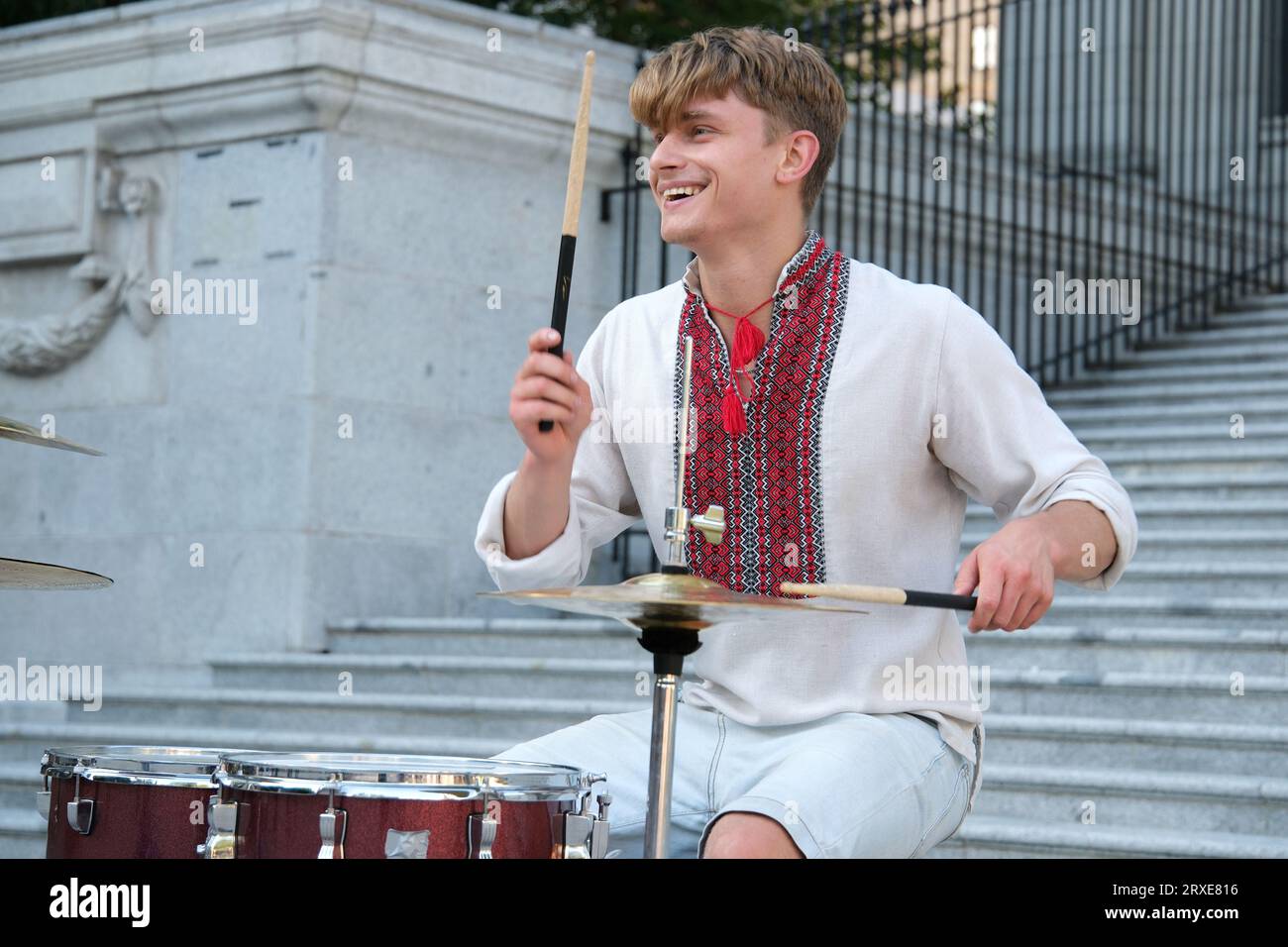 Spielen Sie meisterhaft die Trommel der schöne junge Mann von europäischem Aussehen in ukrainischen bestickten Hemden Nationalkleidung der Ukraine spielt die Trommel wehende Sticks. Kraft der Glücklichkeits-Professionalität Stockfoto