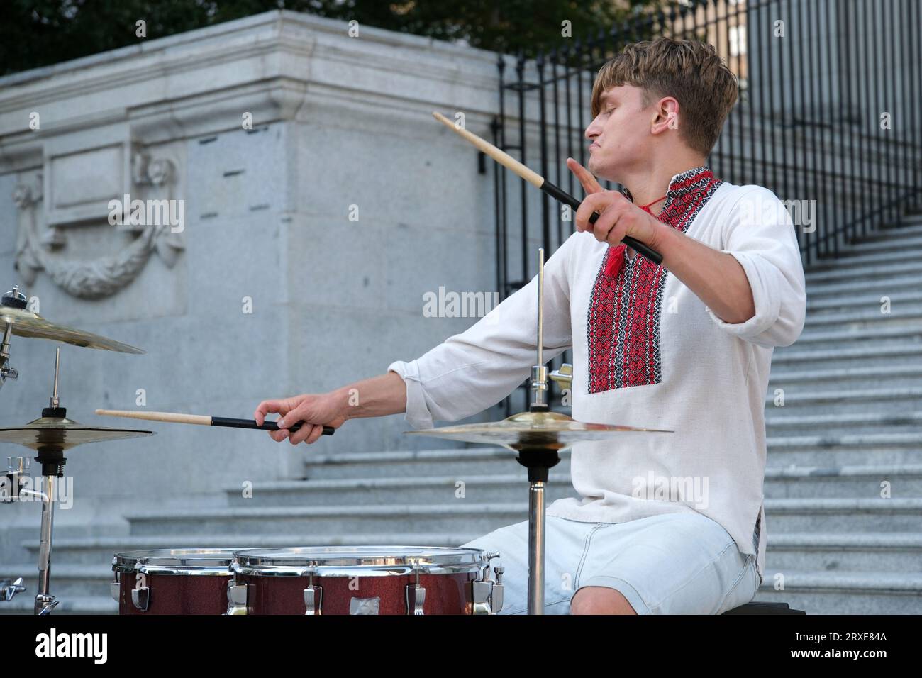 Spielen Sie meisterhaft die Trommel der schöne junge Mann von europäischem Aussehen in ukrainischen bestickten Hemden Nationalkleidung der Ukraine spielt die Trommel wehende Sticks. Kraft der Glücklichkeits-Professionalität Stockfoto