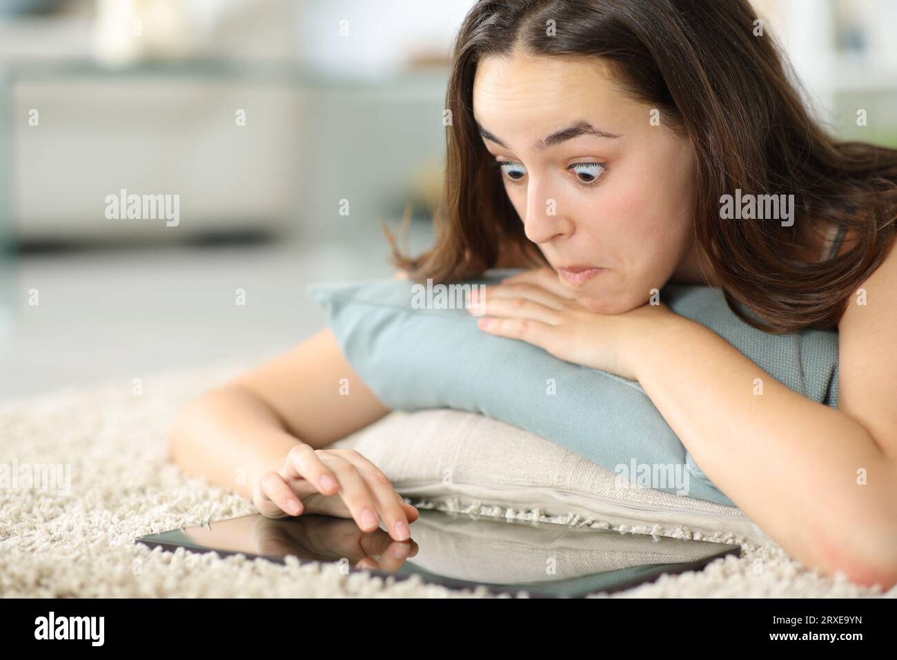 Perplexte Frau, die ein Tablet zu Hause auf dem Boden anlegt Stockfoto