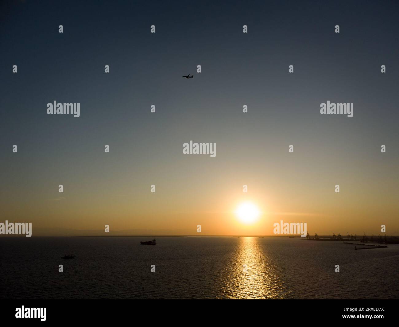 Griechenland, Thessaloniki, september 2023. Schiff und Passagierflugzeug bei Sonnenuntergang in der Bucht von thessalonica in der Nähe des Hafens. Stockfoto