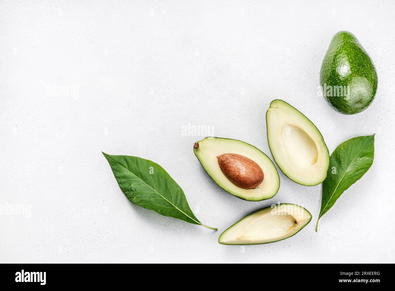 Avocado auf weißem Hintergrund. Hälften roher Avocadofrüchte mit Avocadoblättern. Draufsicht auf Avocado. Stockfoto