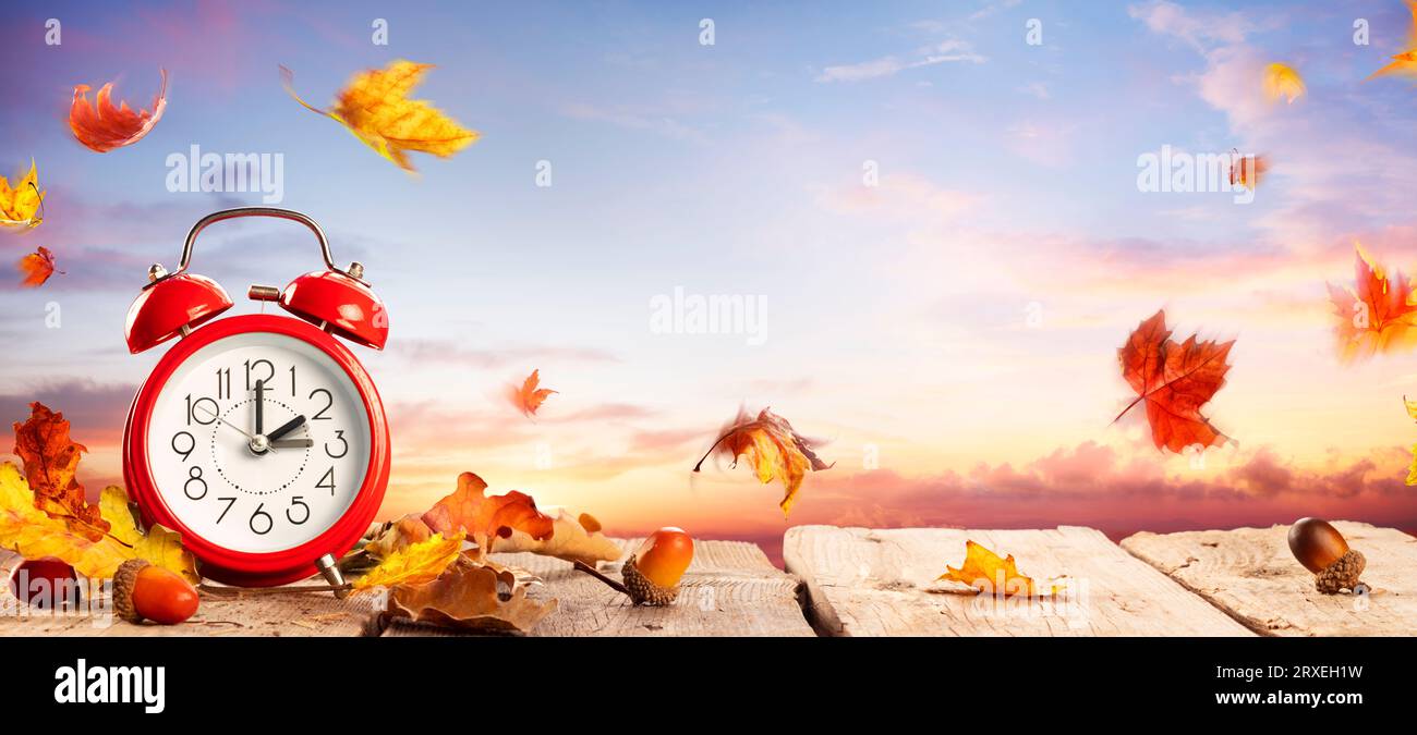 Rückfallzeit - Sommerzeit Ende - Wecker Bei Sonnenaufgang Mit Blättern - Rückkehr Zur Winterzeit Stockfoto