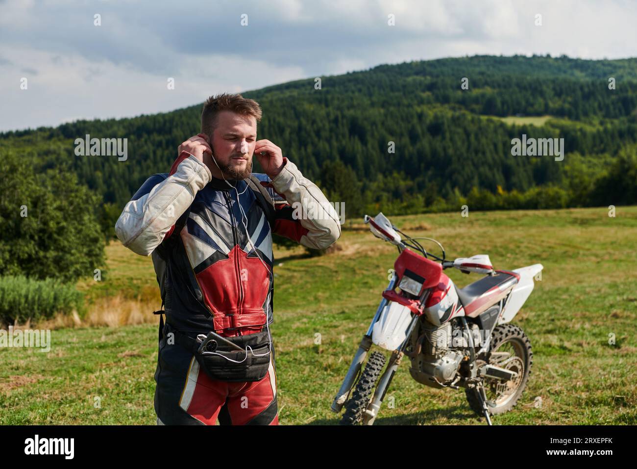 Ein professioneller Motocross-Fahrer in einem Vollanzug, Handschuhen und Rucksack bereitet sich auf ein waghalsiges Abenteuer durch den Wald vor, das auf einen vorbereitet ist Stockfoto