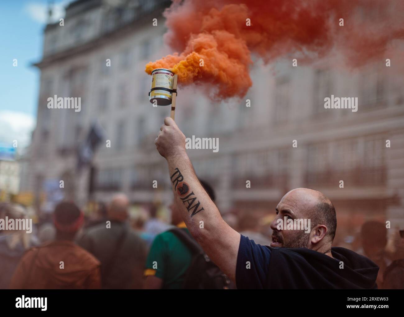 Ein Demonstrant lässt etwas farbigen Rauch ab, während er durch London marschiert und gegen die ULEZ und ihre Expansion protestiert. Stockfoto