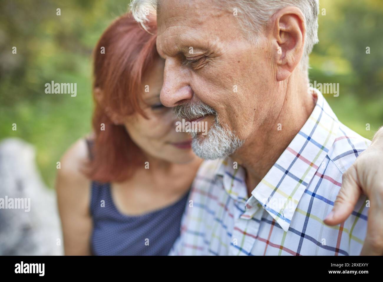 Profilporträt eines ruhigen älteren Mannes, der neben der Frau nach unten schaut Stockfoto