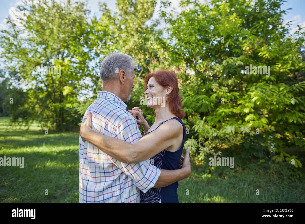 Seniorenfrau lächelt und tanzt mit Seniorenmann Stockfoto