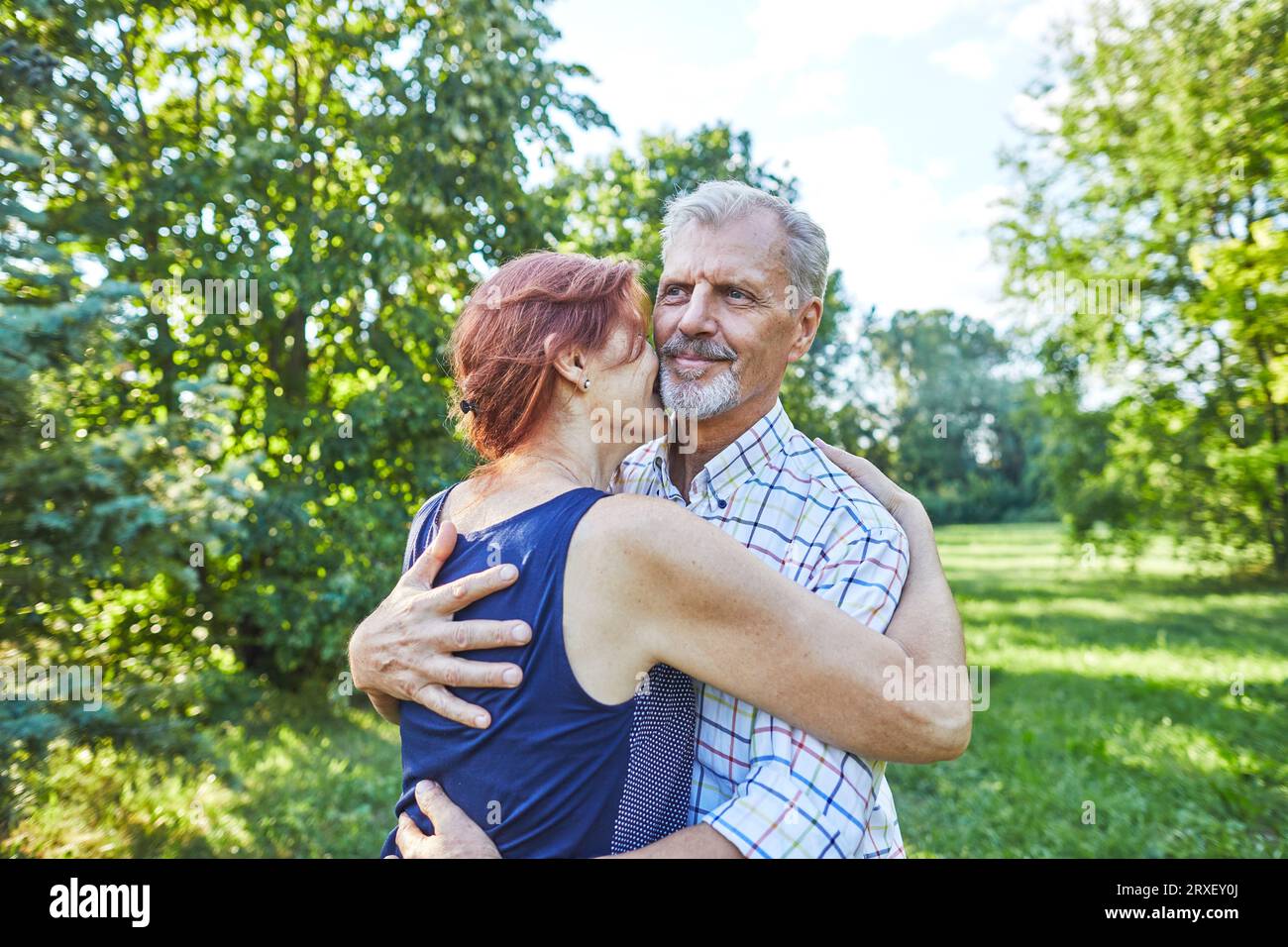 Seniorin umarmt lächelnden Mann im Freien Stockfoto