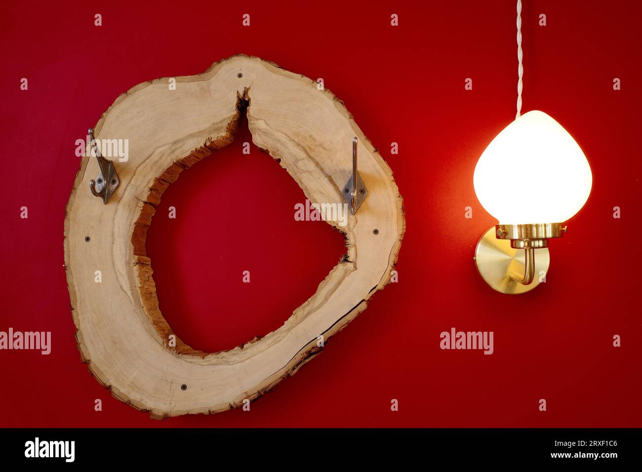 Die Lampe und der Aufhänger sind aus Holz. Vor dem Hintergrund einer knallroten Wand. Ein Element von d Cor Stockfoto