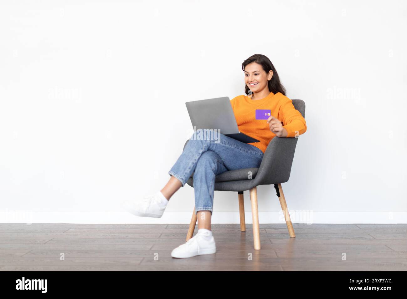 Fröhliche junge indische Frau mit Laptop, Kreditkarte, weißem Hintergrund Stockfoto