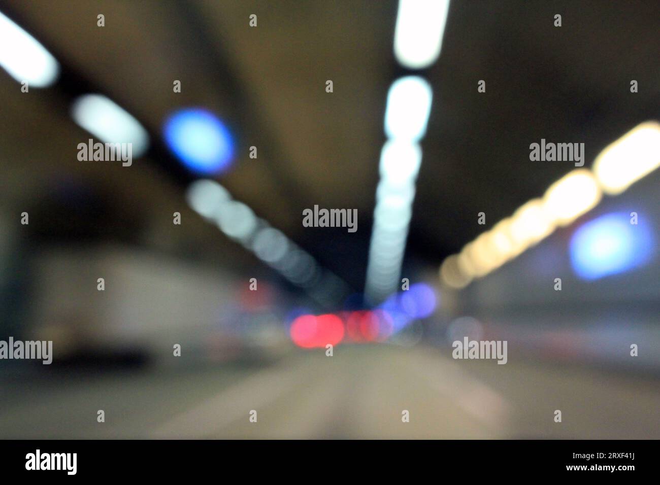 Defokussiertes Bild einer Straße im Tunnel, Bokeh-Lichter. Spur für Autos. Stockfoto